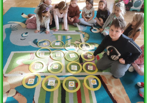 Dzieci z grupy Liski siedzą na dywanie i uczą się układać sudoku z kartami emocji