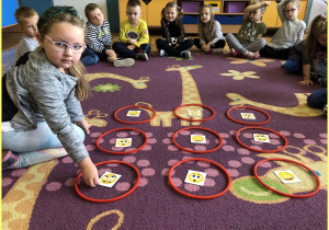 Maja z grupy Jeżyki siedzi na dywanie i uczy się układać sudoku z kartami emocji