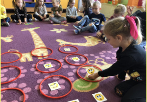 Kaja z grupy Jeżyki siedzi na dywanie i uczy się układać sudoku z kartami emocji