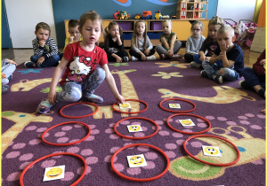 Sara z grupy Jeżyki siedzi na dywanie i uczy się układać sudoku z kartami emocji