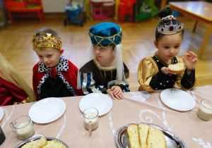 Dzieci siedzą przy stole uroczyście nakrytym.