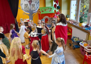 Grupa dzieci w królewskich przebraniach tańczy.