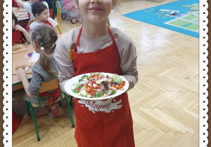 Zuzia pokazuje talerz z surówką zrobioną przez dzieci.