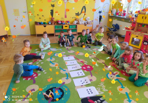 Dzieci siedzą na dywanie, przed nimi koperty z zadaniami.