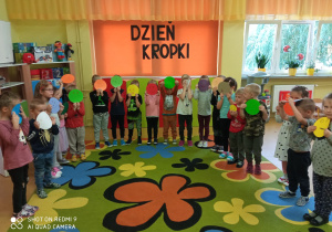 Dzieci z kolorowymi kropkowymi minkami wyciętymi z papieru.