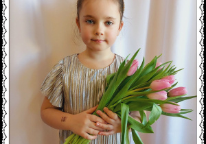 Dziewczynka trzyma różowe tulipany.
