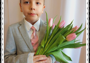 Chłopiec trzyma różowe tulipany.
