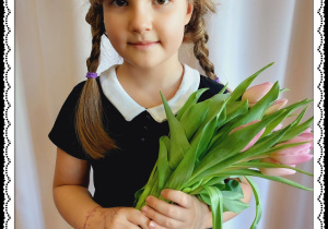 Dziewczynka trzyma różowe tulipany.