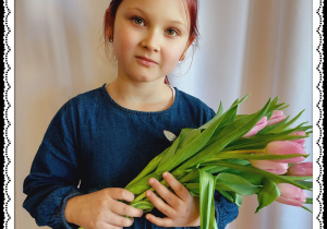 Dziewczynka trzyma różowe tulipany.