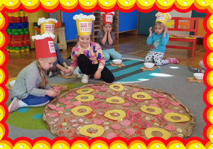 Dzieci ozdabiają papierową pizzę.