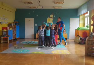 Dzieci trzymają w górze niebieskie piłki.