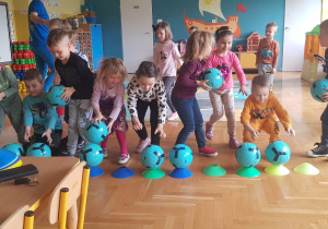 Dzieci biorą niebieskie piłki.