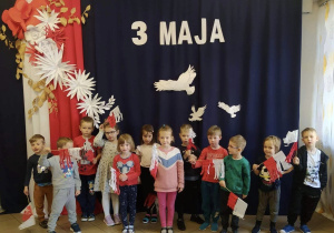 Dzieci z grupy 6, na tle dekoracji z okazji obchodów 3 Maja