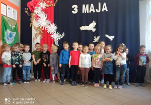 Dzieci z grupy 2, na tle dekoracji z okazji obchodów 3 Maja
