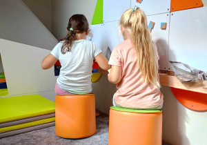 Dziewczynki korzystają z tablicy magnetycznej