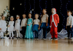 Występ dzieciWystęp dzieci - dziewczynki w złotych bluzkach i granatowych spódniczkach, śnieżynki, Wróżka, Mikołaj i Choinka