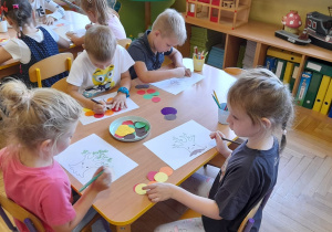 Dzieci w czasie pracy plastycznej przy stoliczku.