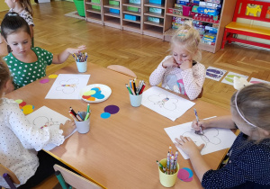 Dzieci w czasie pracy plastycznej przy stoliczku.