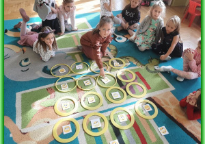 Dzieci z grupy Liski siedzą na dywanie i uczą się układać sudoku z kartami emocji