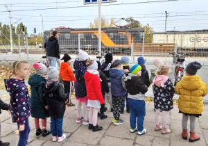 Grupa dzieci obserwuje przejazd pociągu towarowego.