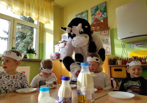 Pani przebrana w krowę, daje dzieciom do powąchania produkty mleczne