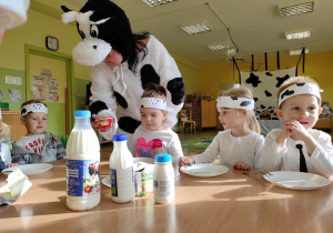 Pani przebrana w krowę, daje dzieciom do powąchania produkty mleczne