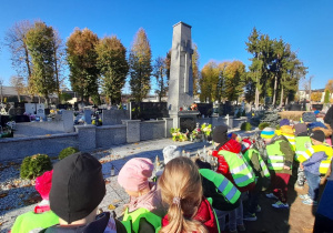 Dzieci stoją przy pomniku żołnierzy