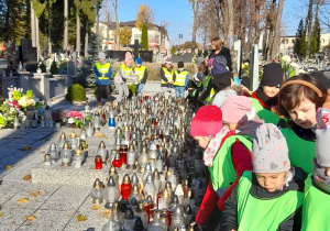 Dzieci ustawiają znicze na pomniku