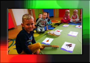 Na zdjęciu grupka dzieci, przed nimi leżą instrumenty