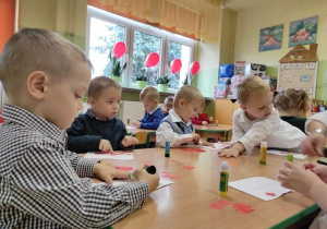 Dzieci przy stoliku wyklejają flagę Polski.