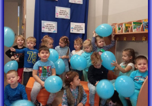 Kotki w niebieskich strojach i z niebieskimi balonami na tle dekoracji Prawa Dziecka