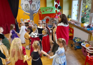 Grupa dzieci w królewskich przebraniach tańczy.