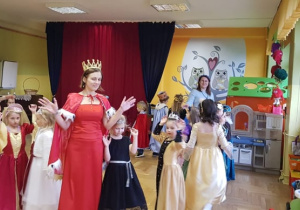 Pani w przebraniu Królowej tańczy wraz z dziećmi.