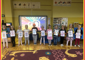 Dzieci stoją i trzymają litery tworzące napis Dzień Kredki w rękach