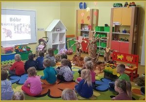 Dzieci oglądają film edukacyjny o przygotowaniach zwierząt do zimy.