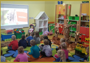 Dzieci oglądają film edukacyjny o przygotowaniach zwierząt do zimy.