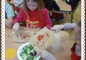 Dzieci ubrane w fartuchy kroją warzywa i owoce na surówkę
