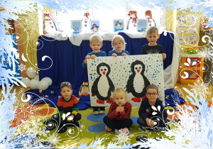 Na zdjęciu grupa dzieci. Chłopcy trzymają namalowane pingwiny.