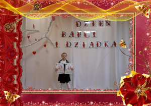 Dziewczynka trzyma w rączkach kartkę z kalendarza, w tle dekoracja okolicznościowa.