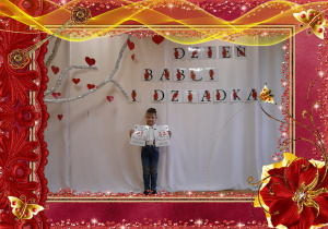 Chłopiec trzyma w rączkach kartkę z kalendarza, w tle dekoracja okolicznościowa