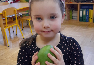 Dziewczynka trzyma w rączkach mango.