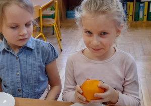Dziewczynka trzyma w rączkach pomarańcze.