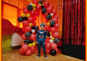 Alan w stroju karnawałowym na tle balonów.