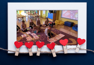 Dzieci układają z liter wyraz Walentynki w ramce z sercami