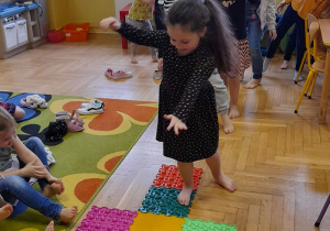Dziewczynka skacze po ścieżce sensorycznej z puzzli.