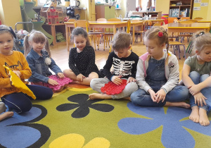 Grupa dzieci podaje sobie z rąk do rąk puzzle sensoryczne.