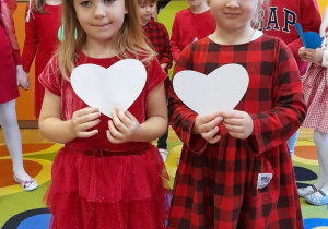 Dziewczynki trzymają białe serca.