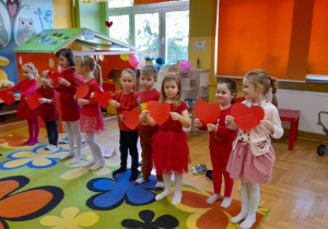 Dzieci trzymają czerwone serca.