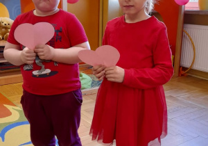 Dzieci trzymają różowe serduszka.