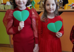 Dziewczynki trzymają zielone serduszka.